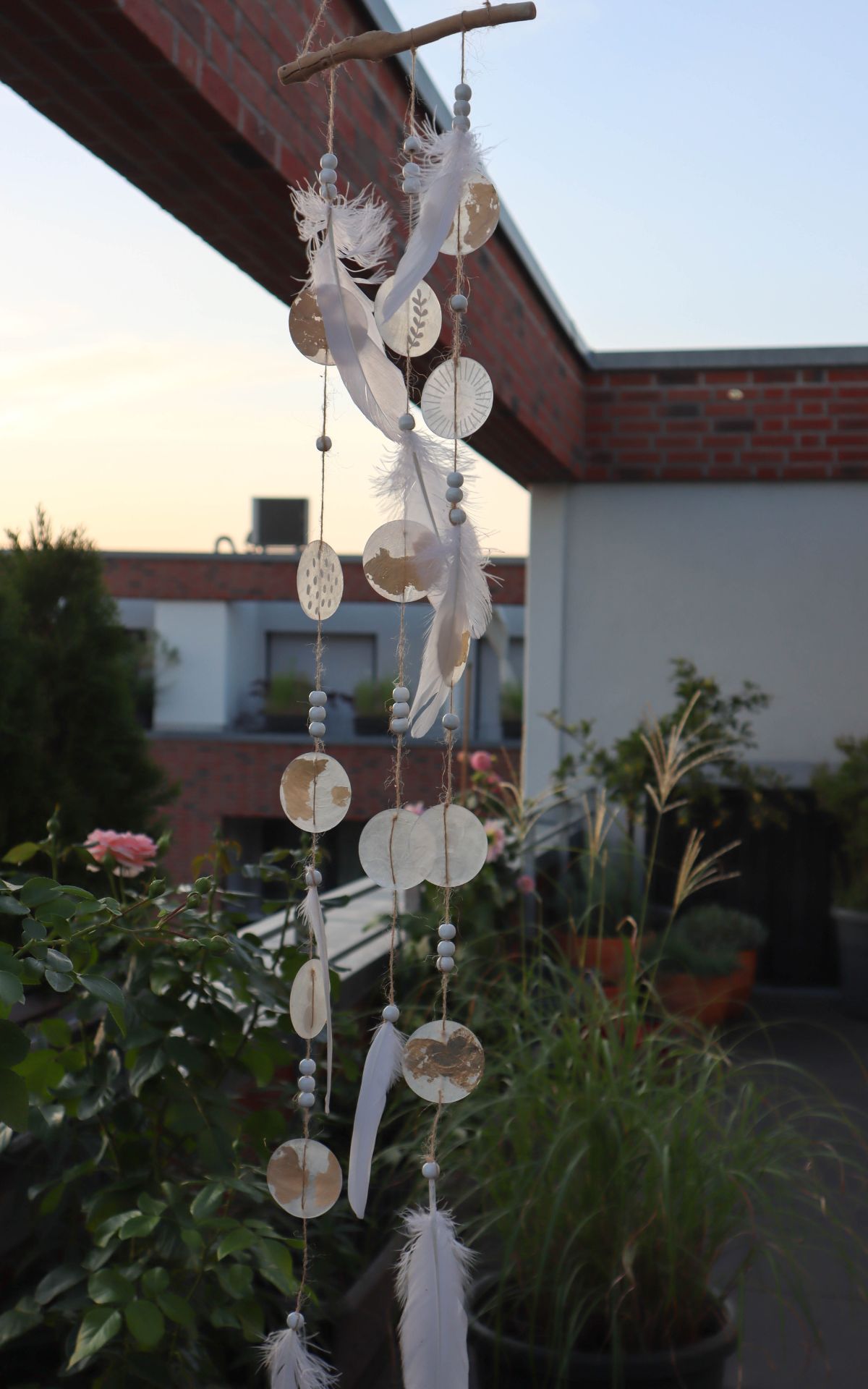 Windspiel basteln aus Naturmaterialien: Ich zeige dir, wie du ein bezauberndes Boho-Windspiel mit Muschelscheiben, Federn und Holzperlen selbst gestalten kannst. Die perfekte DIY-Idee für eine individuelle Garten- oder Hochzeitsdekoration.