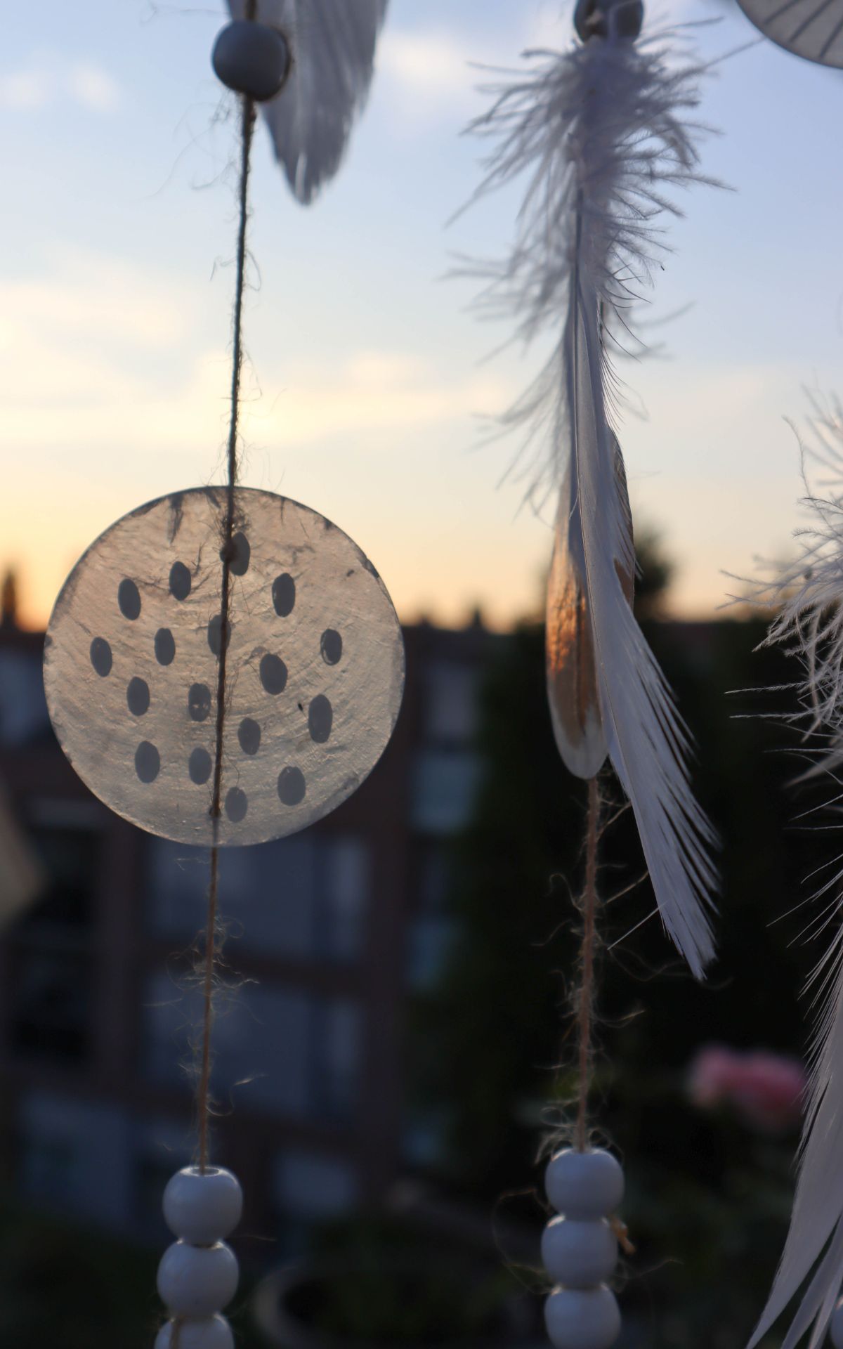 Windspiel basteln aus Naturmaterialien: Ich zeige dir, wie du ein bezauberndes Boho-Windspiel mit Muschelscheiben, Federn und Holzperlen selbst gestalten kannst. Die perfekte DIY-Idee für eine individuelle Garten- oder Hochzeitsdekoration.