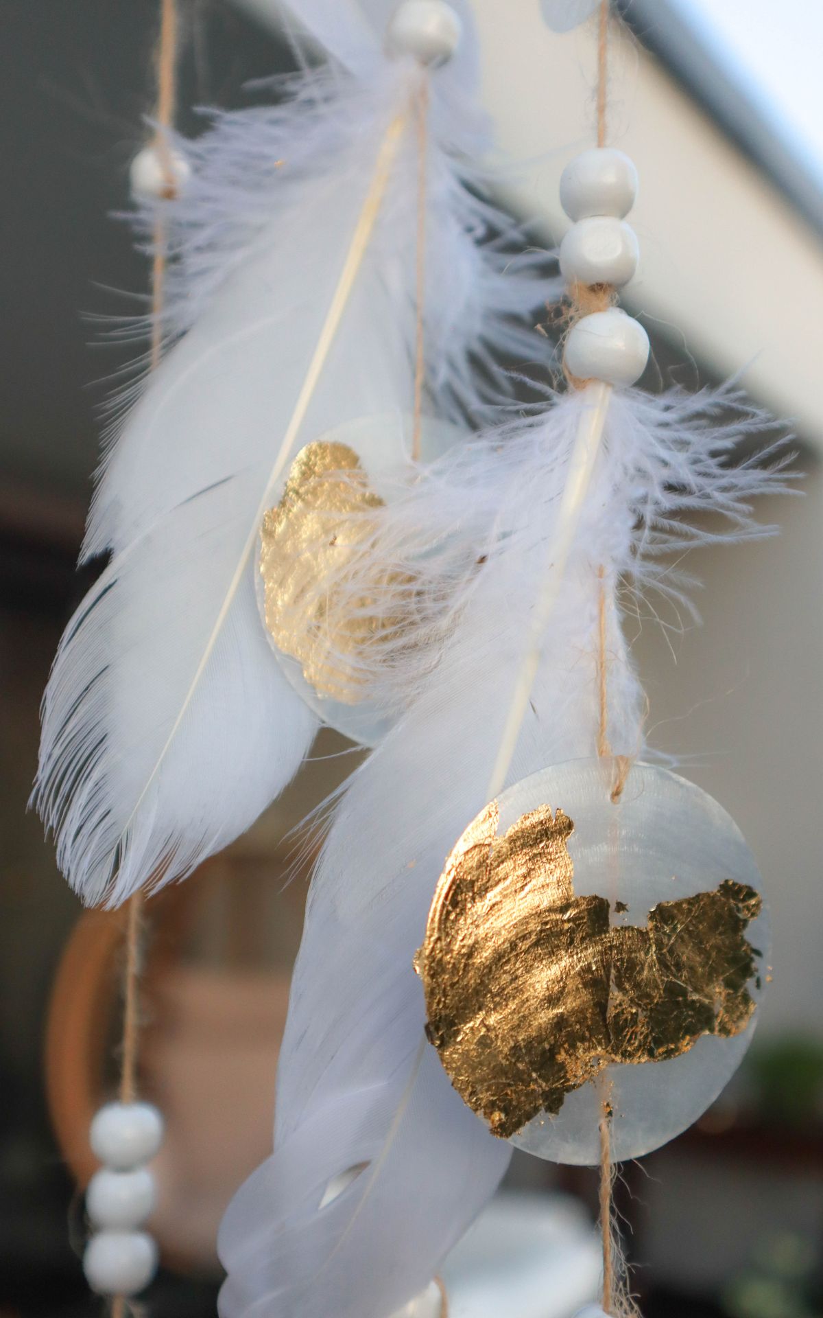 Windspiel basteln aus Naturmaterialien: Ich zeige dir, wie du ein bezauberndes Boho-Windspiel mit Muschelscheiben, Federn und Holzperlen selbst gestalten kannst. Die perfekte DIY-Idee für eine individuelle Garten- oder Hochzeitsdekoration.